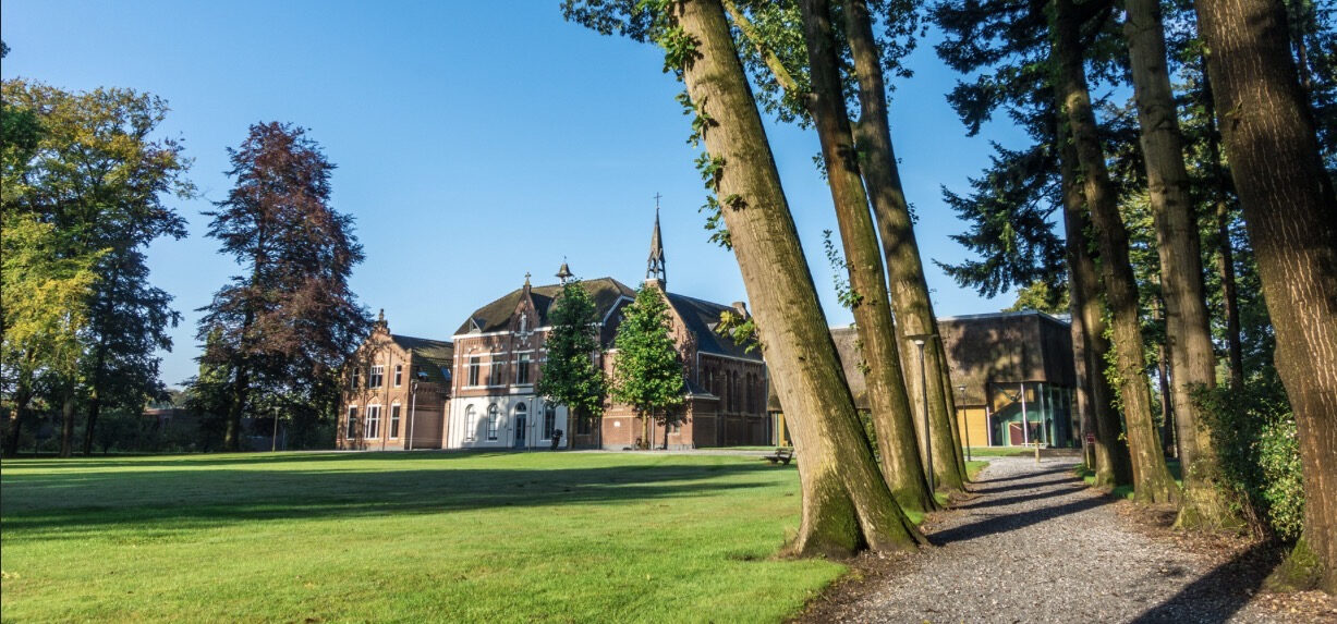 Kloostertuin van Klooster ZIN in Vught, met oude bomen en grasveld